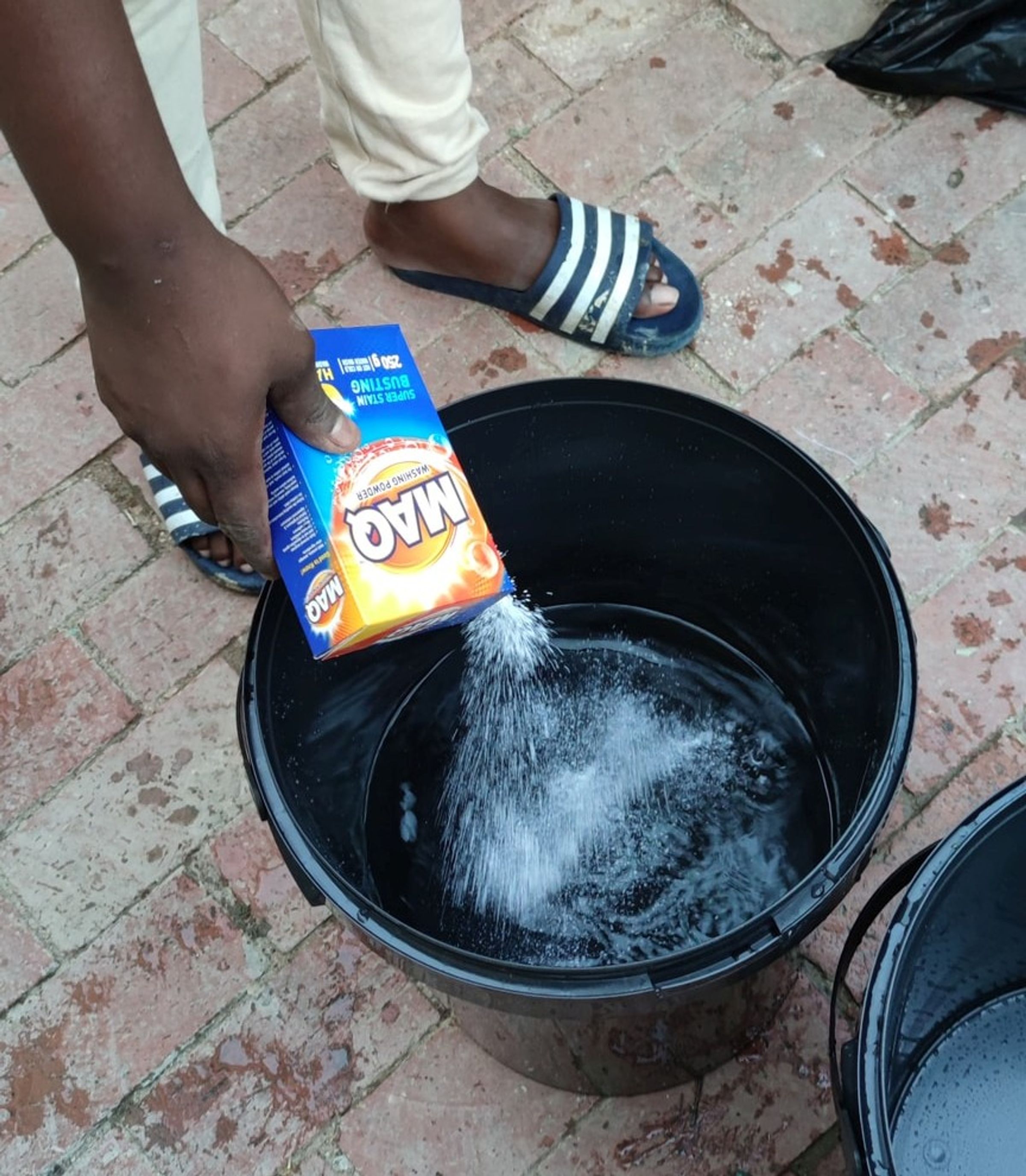 Putting some detergent into a half-full bucket